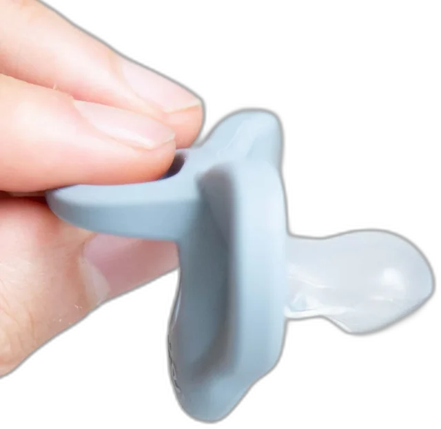 A hand holding the patented Minbie orthodontic dummy