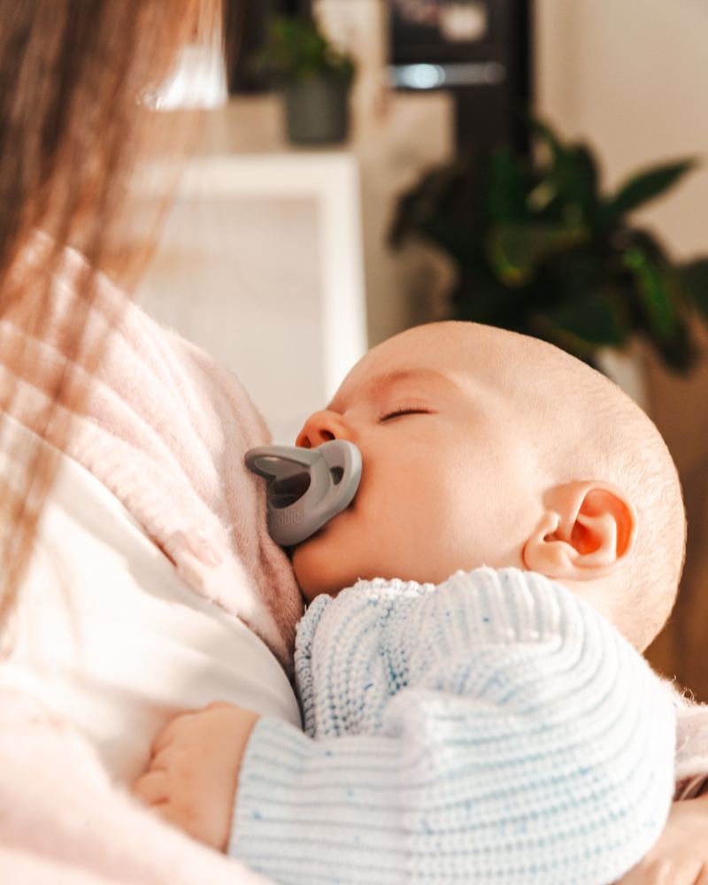 A sleeping baby with a Grey Minbie dummy