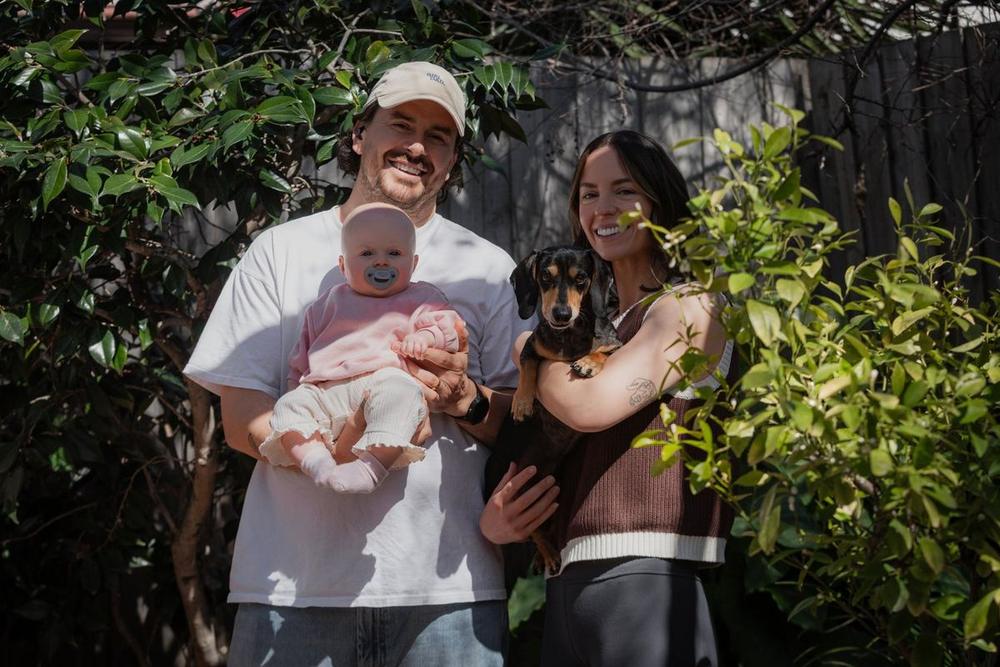 Parents with their baby and dog in a sunlit garden