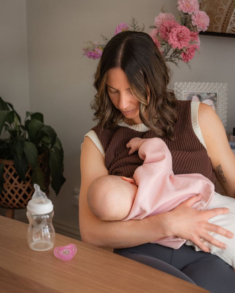 A mum breastfeeding with a Minbie bottle and pink dummy on the table